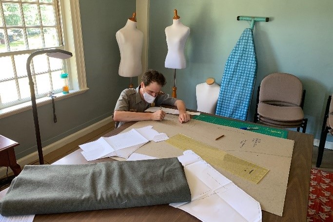 Ranger Jarrad is tracing patterns onto cardboard in the historical clothing workshop.