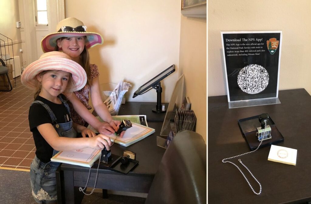 Two girls in summer hats stand at a table and stamp their passport. 